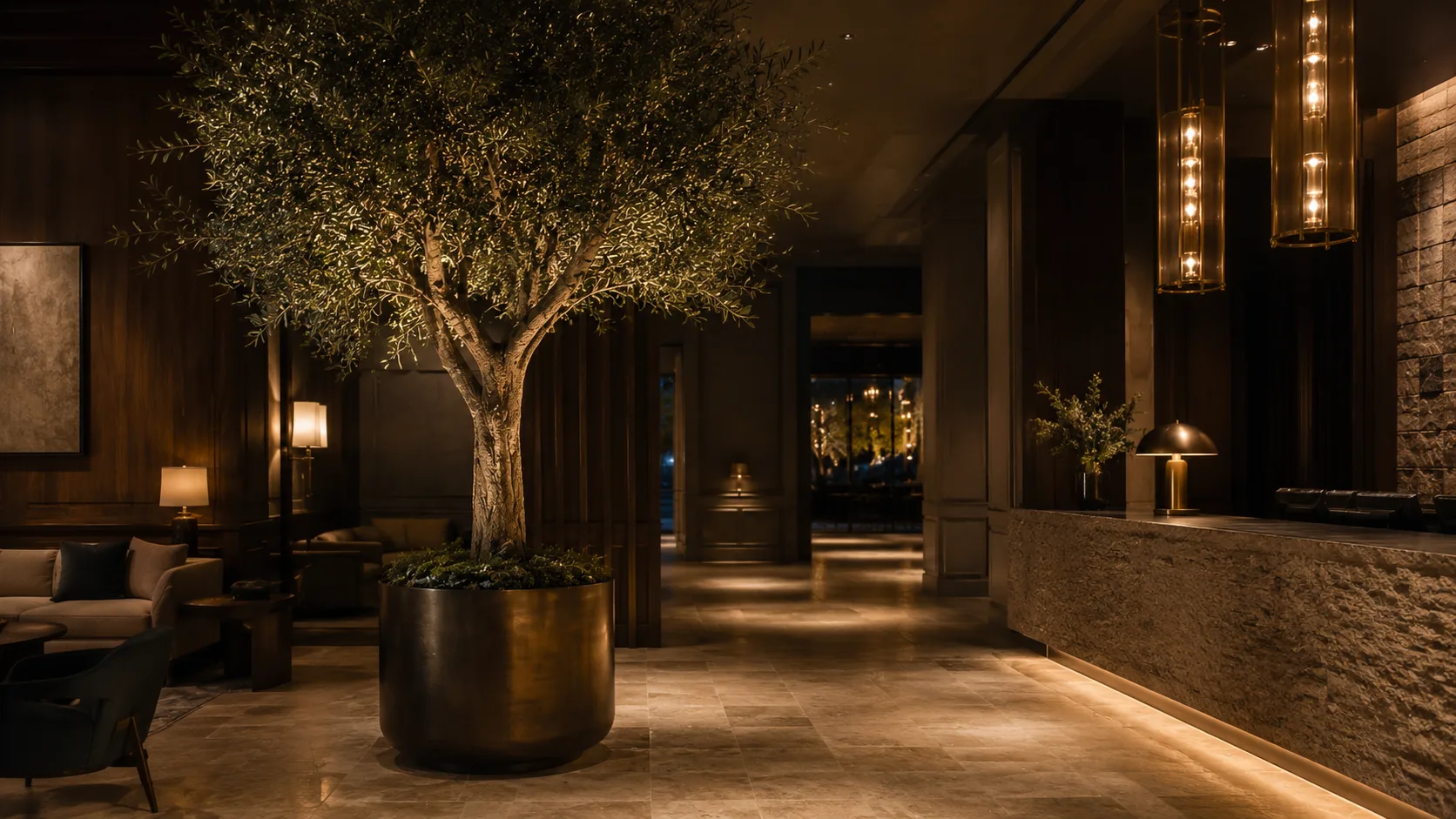 Large artificial olive tree in a boutique hotel lobby with warm architectural lighting